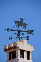 a weather vane on top of a brick building with a horse and rider photo