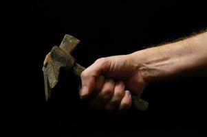 a hand holding a hammer on a black background photo