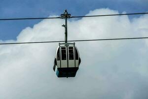 un cable coche suspendido en el aire con nubes en el antecedentes foto