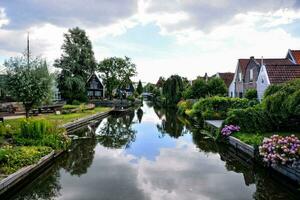 a canal in the middle of a town with houses and flowers photo