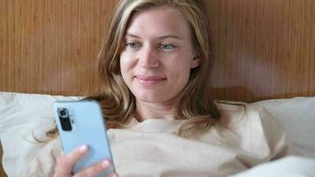 joven mujer utilizando teléfono inteligente en hotel cama después despertar arriba video