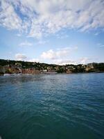 Photo of a scenic view of houses on a hill overlooking a beautiful body of water