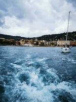 Photo of a sailboat sailing near a picturesque coastal town