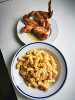 Photo of a delicious plate of chicken wings and pasta on a tabl
