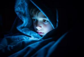 young boy engrossed in a tablet or mobile screen with a blanket draped over his head. AI Generated photo