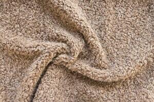 New soft brown curly teddy fleece plush throw blanket or pillow case. Abstract fabric texture background with curles. Top view, closeup photo