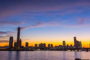 Seúl ciudad rascacielos a noche a lo largo el Hangang río después puesta de sol a crepúsculo y el cielo con hermosa colores a yeuido, sur Corea. foto