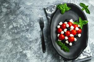 Caprese with cherry tomatoes, mini mozzarella, fresh basil leaves, Traditional italian food, antipasto. banner, menu, recipe place for text, top view photo