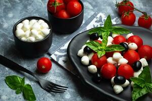 clásico italiano ensalada caprese servido en original formar con Cereza Tomates, mini mozarella perlas, albahaca hojas y balsámico vidriar foto