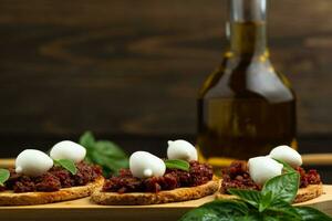 Bruschetta con seco Tomates, queso Mozzarella y albahaca en de madera antecedentes. Copiar espacio foto