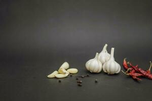 Red chilli peppers with garlic cloves on black background photo