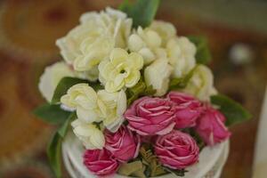 un ramo de flores de blanco rosas en un taza en un de madera mesa foto