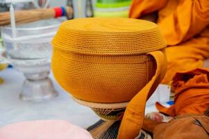 A metal alms bowl covered with golden-orange cloth to receive food from laypeople and people who believe in Buddhism. photo