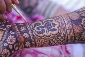 Young woman mehendi artist painting henna on the bride's hand photo