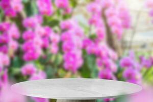 Empty marble table top with blur orchid garden background for product display photo