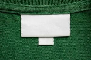 Blank white laundry care clothes label on green shirt fabric texture background photo