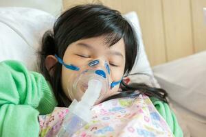 Sick little asian girl inhalation with nebulizer for respiratory treatment photo