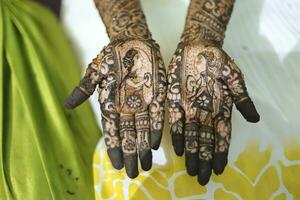 An Indian bride showing her hand's mehndi tattoos design photo