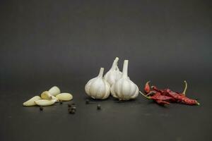 Red chilli peppers with garlic cloves on black background photo