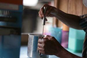 mano de indonesio calle vendedor prepara un vaso de con hielo foto