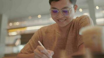 asiatico dell'uomo mani fare compiti a casa su tavoletta, all'aperto in linea apprendimento concetto video