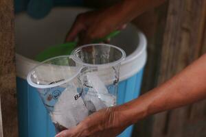 Hand of Indonesian street vendor prepares a glass of iced photo