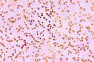 Trendy rose gold foil confetti stars on pink background. Christmas festive abstract backround. Birthday party, New Year, Christmas celebration, holidays, winter and dreams concept photo