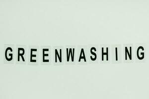 Text GREENWASHING on green background. Green PR, green marketing and misleading information about company products being ecofriendly concept photo