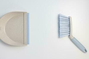 Garbage bin scoop set. Plastic gray and blue dustpan and hand brush on white background. Home cleaning, domestic chores concept. Top view, copy space photo