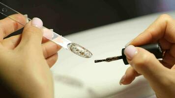 A manicurist applies gel nail polish to empty tips as a sample video