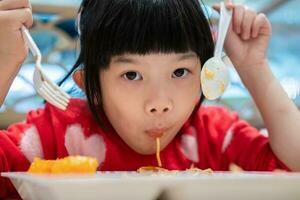 linda pequeño asiático niño niña comiendo comida foto