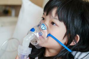 Sick little asian girl inhalation with nebulizer for respiratory treatment photo