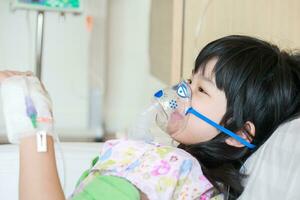 Sick little asian girl inhalation with nebulizer for respiratory treatment photo