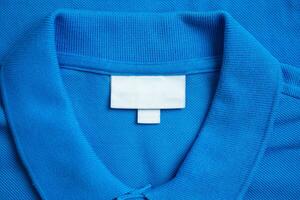 Blank white laundry care clothes label on blue shirt fabric texture background photo