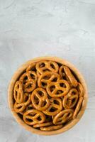 Traditional salty mini pretzels in wooden bowl on gray backround. Top view, copy space photo
