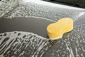 coche limpieza y Lavado con amarillo esponja y espuma jabón foto