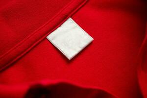 Blank white laundry care clothes label on red shirt fabric texture background photo