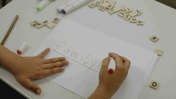 un' bambino scrittura su un' pezzo di carta con un' marcatore video