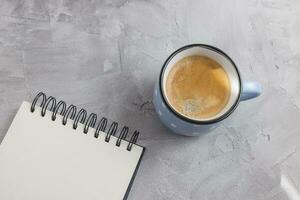Mockup. Open sketchpad or notebook on artist desk workspace, coffee in blue retro style ceramic cup on gray background. Creative concept, empty page. Top view, copy space photo