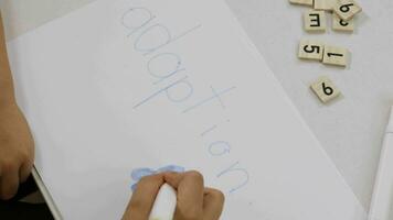 un' bambino scrittura su un' pezzo di carta con un' marcatore video