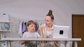 une femme et une enfant séance à une table avec une portable video