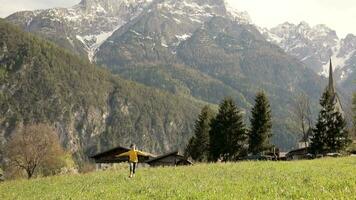 ein jung Mädchen ist Laufen durch ein Feld mit Berge im das Hintergrund video