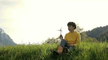 een jongen zittend in de gras met een wind turbine video