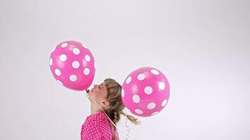 un pequeño niña en un polca punto vestir participación dos rosado globos video