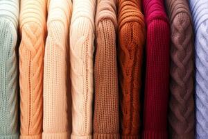 Warm wool sweaters hang on hangers in a row. AI generated. photo