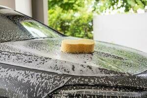 car cleaning and washing with yellow sponge and foam soap photo