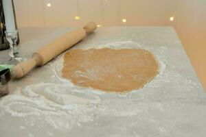 Ginger dough on the kitchen table next to a rolling pin and cookie cutters.. photo