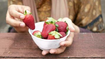 main choisir mûr rouge des fraises dans une bol sur table . video