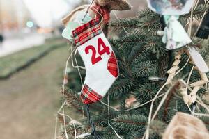 Handmade Christmas sock decoration with number or date 24 on a Christmas tree, outdoors. DIY for children. Environment, recycle, reuse, upcycling and zero waste concept. Selective focus, copy space photo