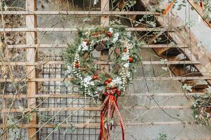 DIY Christmas wreath with pine cones and red decoration on wall photo